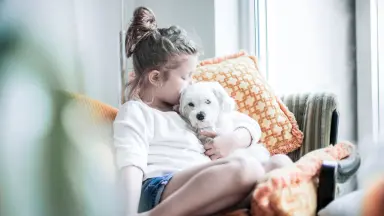 Junge Frau küsst großen Hund an der Wange